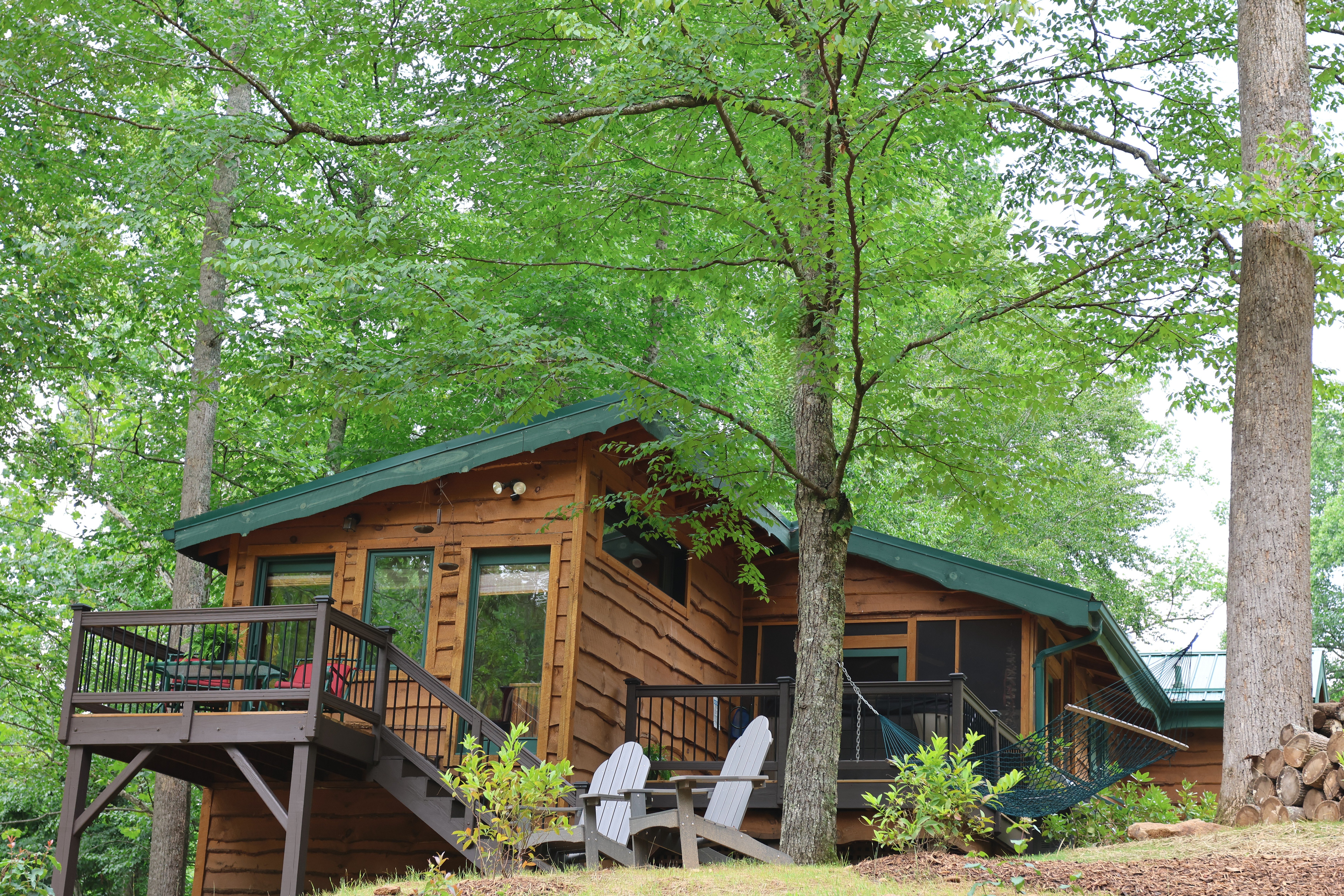Cabin exterior with multiple porches, hammock, and Adirondack chairs